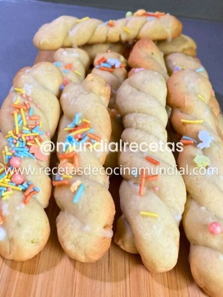 Galletas trenzadas de limón con glaseado y sprinkles sobre tabla de madera