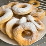 Roscas de naranja caseras espolvoreadas con azúcar glass sobre plato de presentación