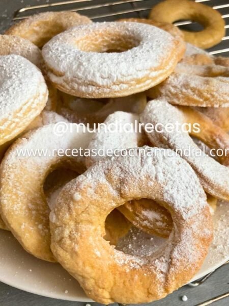 Roscas de naranja caseras espolvoreadas con azúcar glass sobre plato de presentación