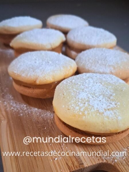 Alfajores peruanos de maicena rellenos con manjar de olla dispuestos sobre una tablita de madera listos para servir.