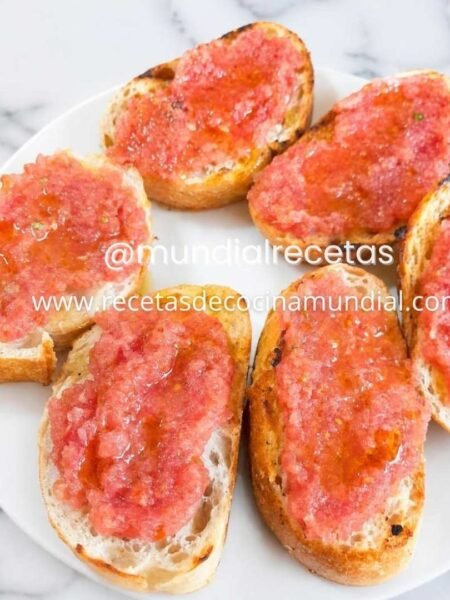 Pan con tomate tradicional servido en un plato con pan rústico tostado, tomate fresco rallado y aceite de oliva virgen extra.
